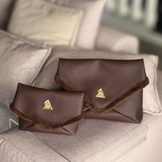 The Amara Duo from t•Ana Couture’s Chocolate Edit features two luxury multi wear clutch bags; one Grande and one Petite; designed to be worn together or individually. Crafted in plush chocolate brown faux fur and finished with gold logo hardware, the Amara bags bring warmth, texture and refined slow luxury to any look. Each piece can be styled as a clutch, shoulder bag or crossbody, offering versatile day to evening wear.