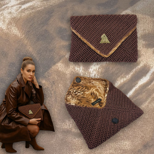 t•Ana Couture Terra Litha Knit Clutch Handbag in rich earthy brown with gold velvet trim and tiger-print interior lining; handmade luxury knit bag styled with brown coat; sustainable, Mediterranean-inspired design. Exceptional luxury design handbag. Elevated luxury brand vibes for high value women.