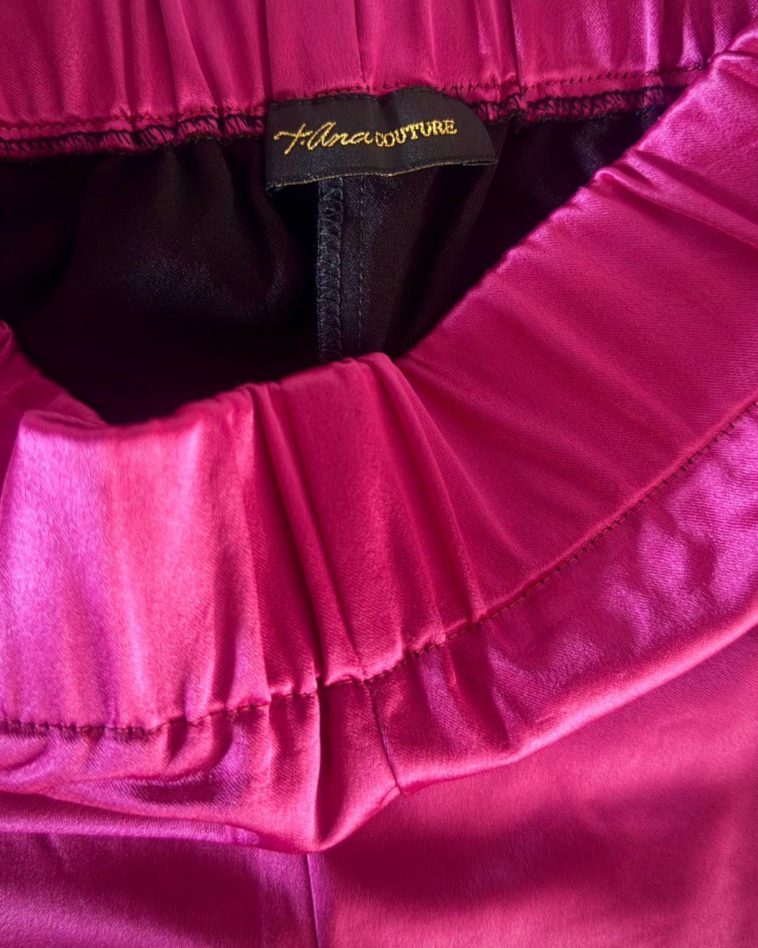 Luxury details and close-up of High-quality t•Ana Couture brand label inside luxury fuchsia satin shorts with Armani brand stretch fabric; captured under Mediterranean sunlight with divine flow and effortless elegance. 