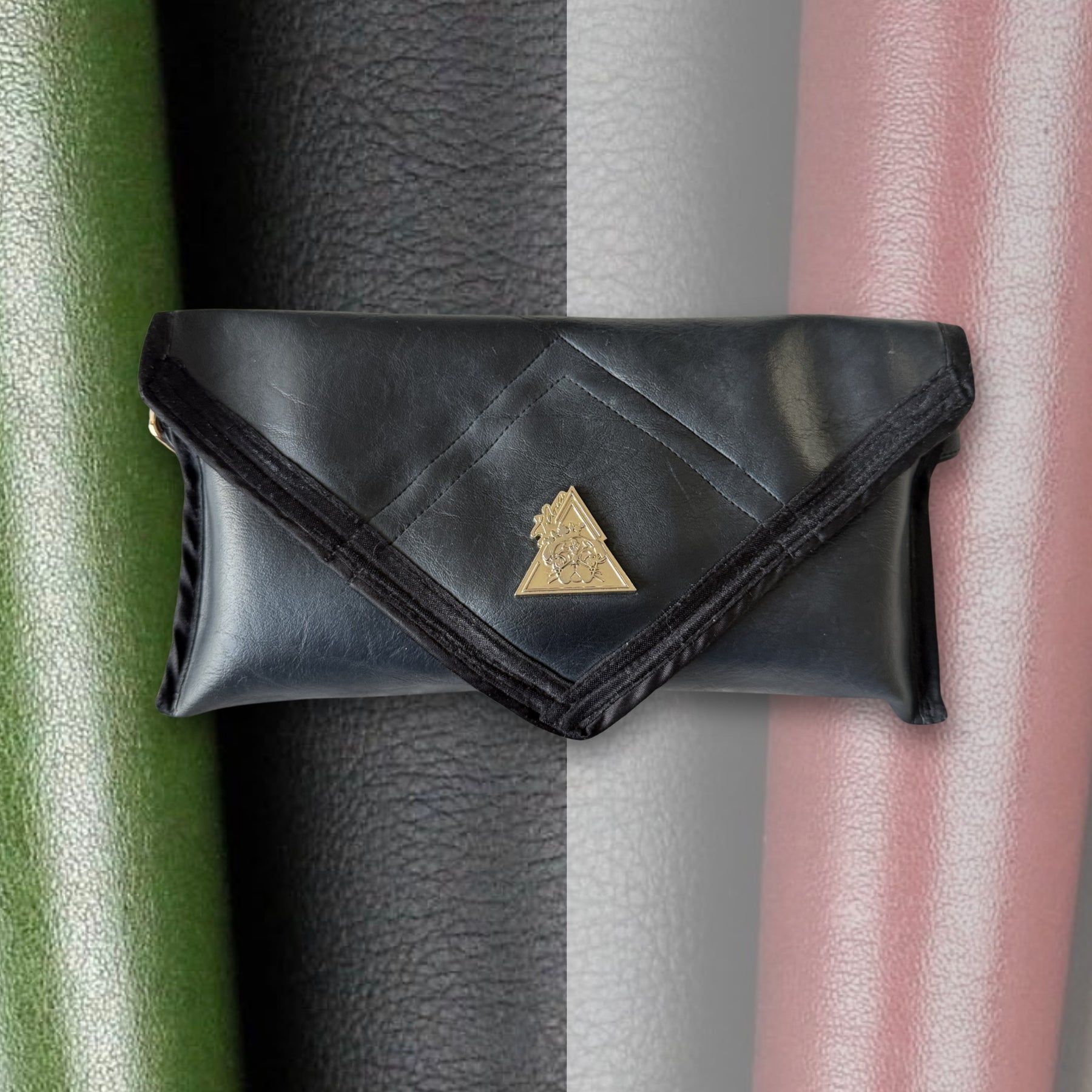 Black Desserto cactus leather clutch bag with background showing multiple cactus leather color variations including green, black, beige and blush tones