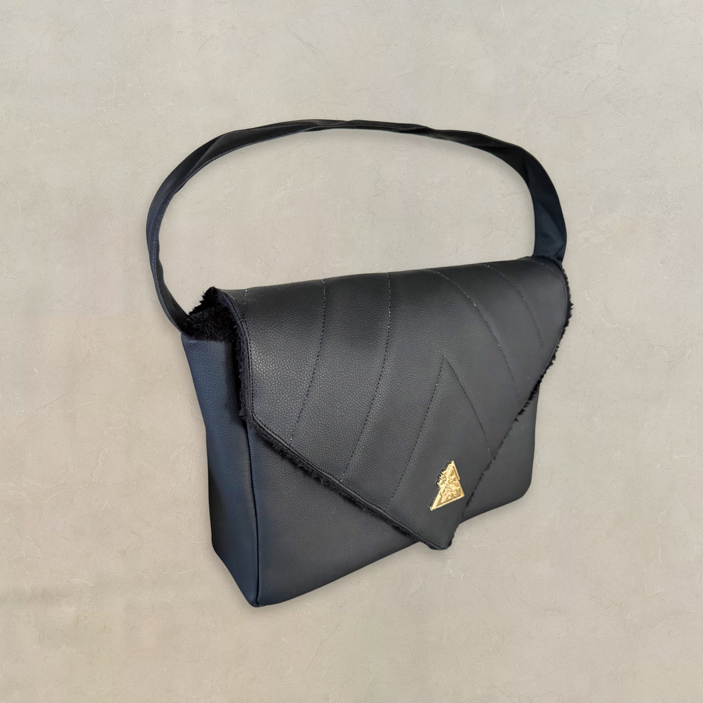 Side base perspective of the El Clásica Elysian Eclipse CarryAll Mini handbag showcasing structured geometric form, premium black vegan leather texture, and architectural luxury handbag craftsmanship by t•Ana Couture.