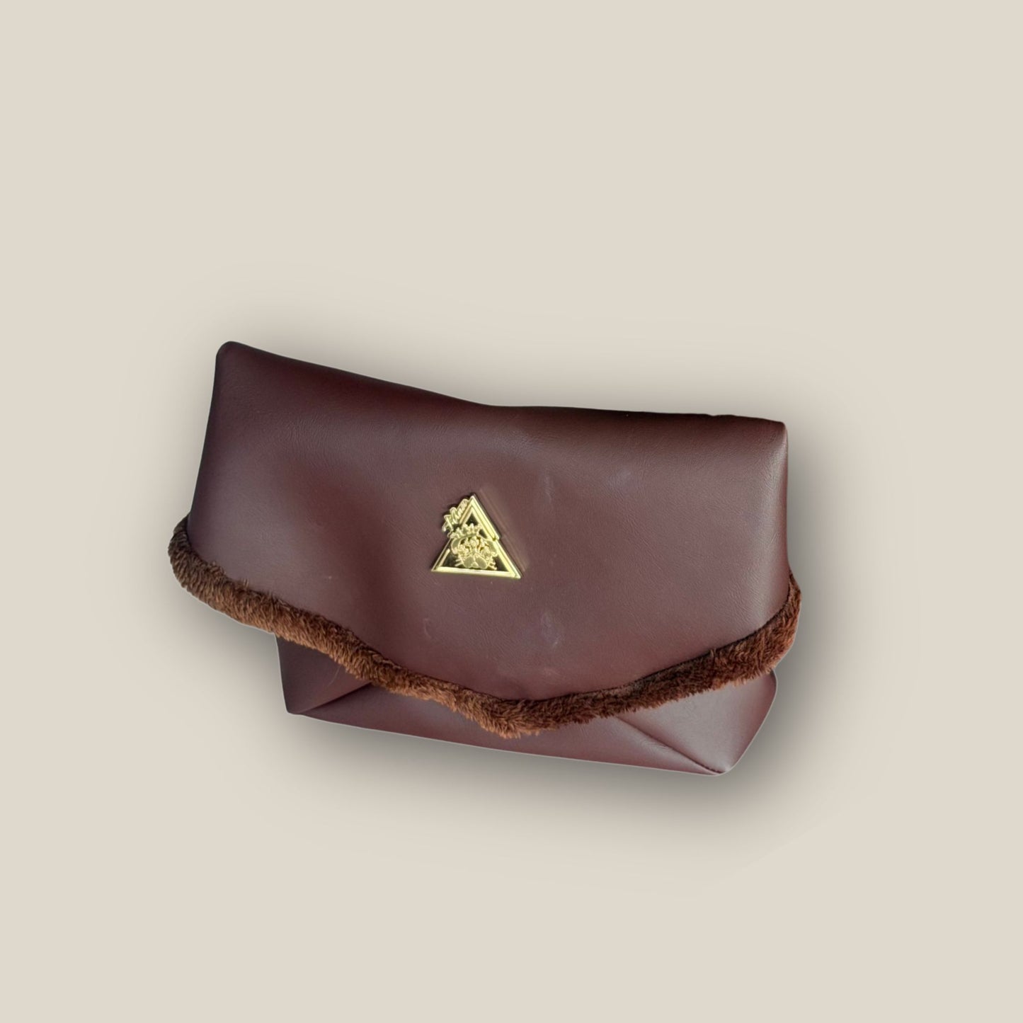 The Amara petite small brown bag from t•Ana Couture’s Chocolate Edit from the Amara Duo. Crafted in plush chocolate brown faux fur and finished with gold logo hardware, the Amara bags bring warmth, texture and refined slow luxury to any look. Each piece can be styled as a clutch, shoulder bag or crossbody, offering versatile day to evening wear. Here we feature the petite or small size bag.