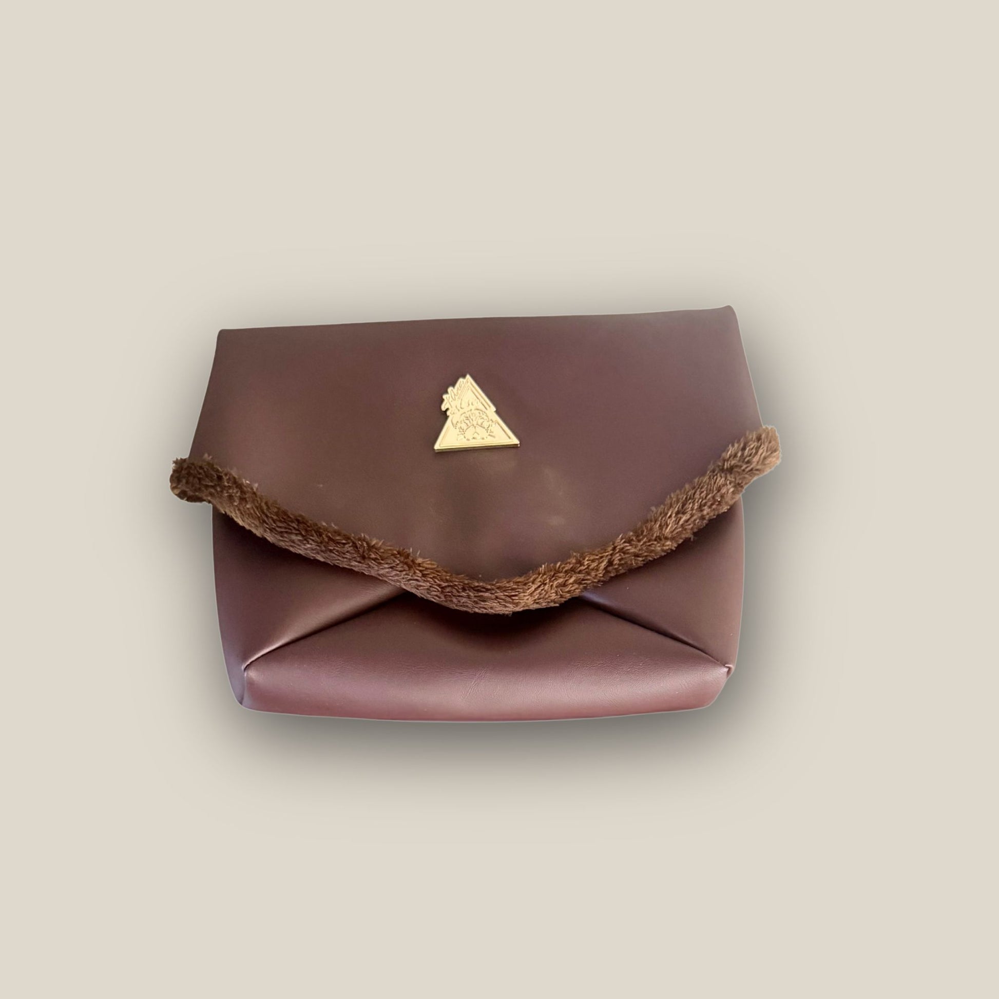 The Amara petite small brown bag from t•Ana Couture’s Chocolate Edit from the Amara Duo. Crafted in plush chocolate brown faux fur and finished with gold logo hardware, the Amara bags bring warmth, texture and refined slow luxury to any look. Each piece can be styled as a clutch, shoulder bag or crossbody, offering versatile day to evening wear. Here we feature the petite or small size bag.