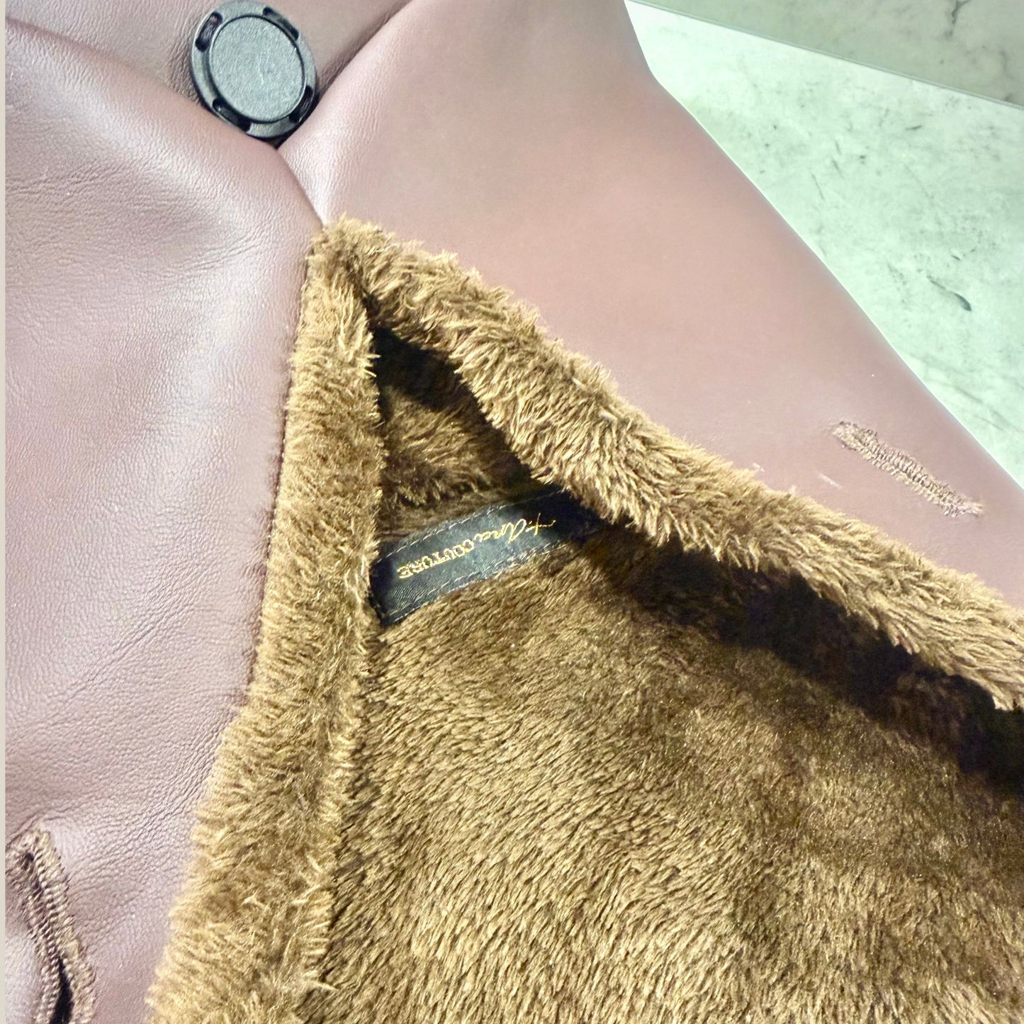 The Amara petite small brown bag from t•Ana Couture’s Chocolate Edit from the Amara Duo. Crafted in plush chocolate brown faux fur and finished with gold logo hardware, the Amara bags bring warmth, texture and refined slow luxury to any look. Each piece can be styled as a clutch, shoulder bag or crossbody, offering versatile day to evening wear. Here we feature the petite or small size bag. Here is the interior lining plush faux fur.