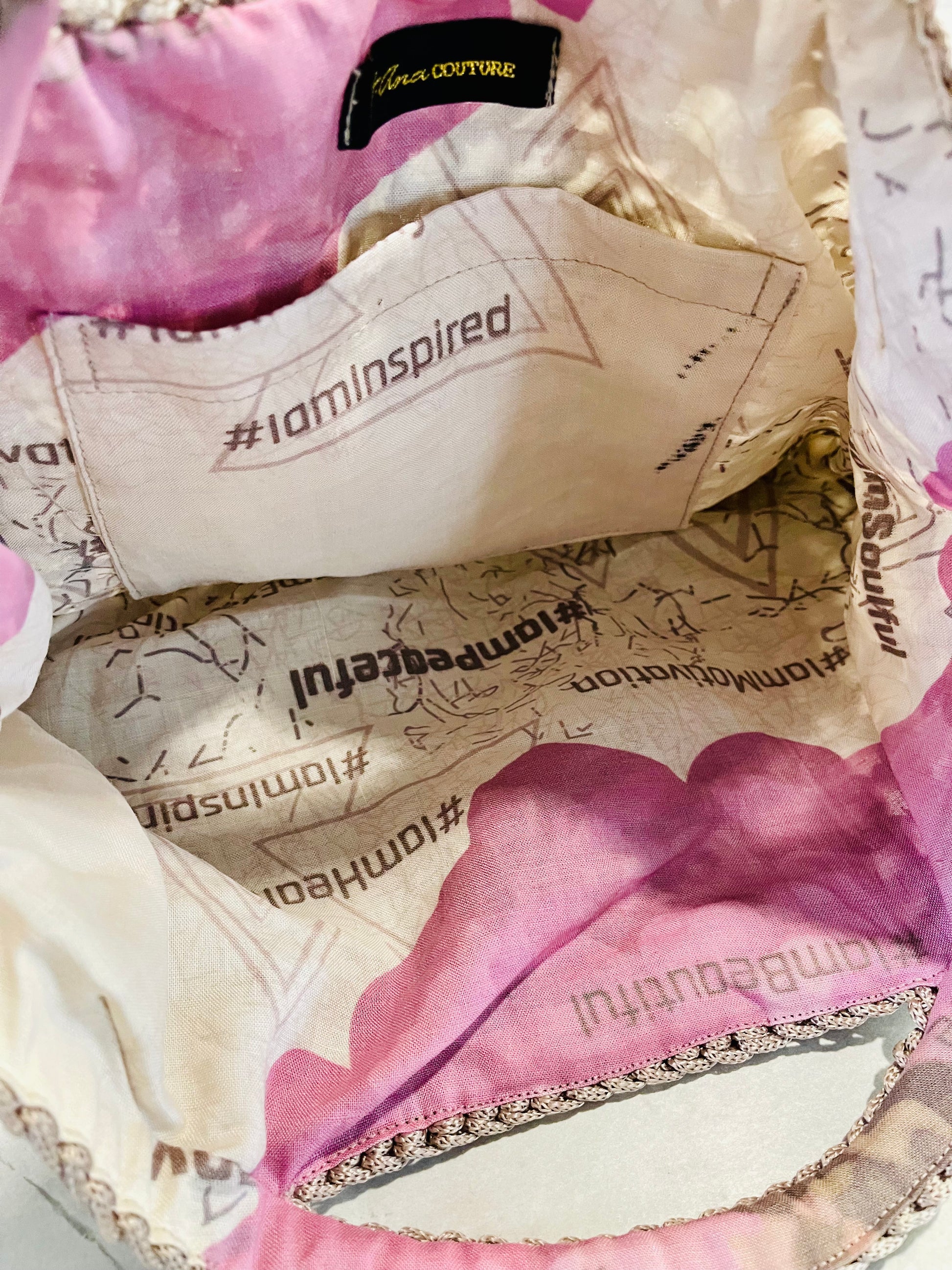 Interior of Mystic Mocha Bloom knit handbag showing organic linen floral lining with zinnia artwork symbolising lasting love, goodness and constancy; signature t.Ana Couture design. Organic linen interior lining of Mystic Mocha Bloom knit handbag featuring bespoke floral artwork, printed affirmations and Zinnia symbolism for lasting love, goodness and constancy; Threads of Heritage Mediterranean Muse Sand and Sea Tribute Collection by t.Ana Couture.