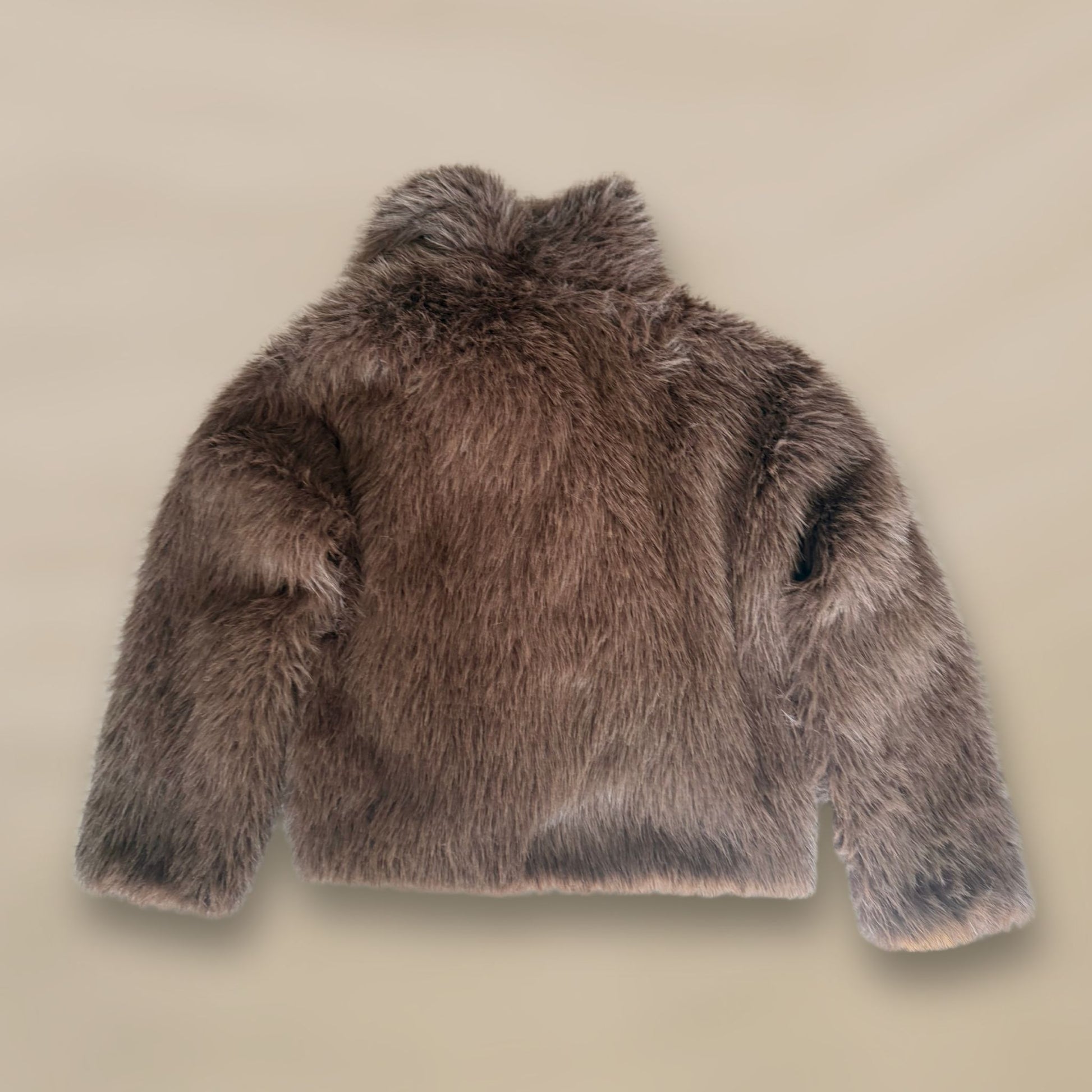 Soft brown faux fur coat featuring natural wooden buttons and practical pockets; a plush, cosy and elegant neutral outerwear piece for women, designed for slow luxury winter styling and refined day to evening looks. This warm, timeless coat elevates everyday outfits with texture, comfort and effortless sophistication. Back side.