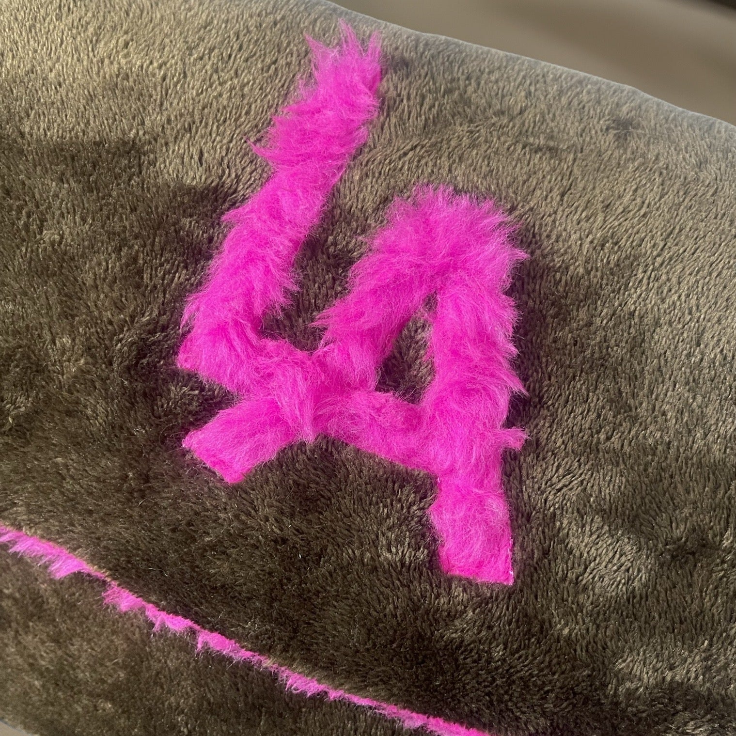 t•Ana Couture LA SnugglePlush Elegante handbag in brown faux fur with bold pink plush trim and LA lettering; luxury statement clutch styled with cream coat; sustainable upcycled design with modern street-luxe elegance.