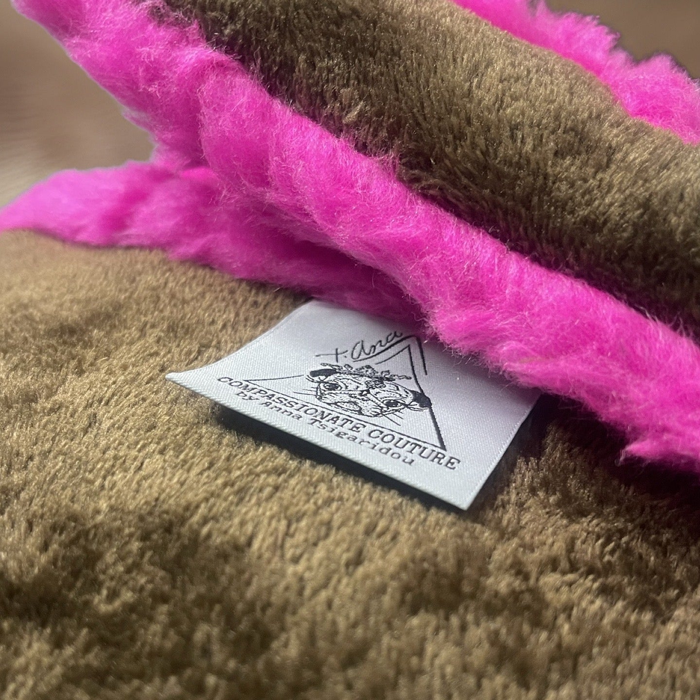 t•Ana Couture LA SnugglePlush Elegante handbag in brown faux fur with bold pink plush trim and LA lettering; luxury statement clutch styled with cream coat; sustainable upcycled design with modern street-luxe elegance.