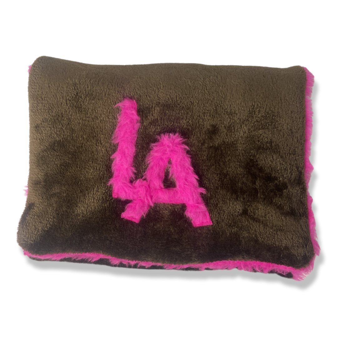 t•Ana Couture LA SnugglePlush Elegante handbag in brown faux fur with bold pink plush trim and LA lettering; luxury statement clutch styled with cream coat; sustainable upcycled design with modern street-luxe elegance.