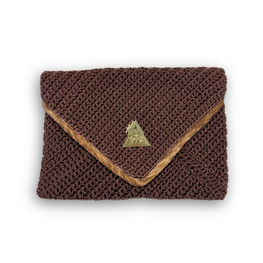 t•Ana Couture Terra Litha Knit Clutch Handbag in rich earthy brown with gold velvet trim and tiger-print interior lining; handmade luxury knit bag styled with brown coat; sustainable, Mediterranean-inspired design. Exceptional luxury design handbag. Elevated luxury brand vibes for high value women.