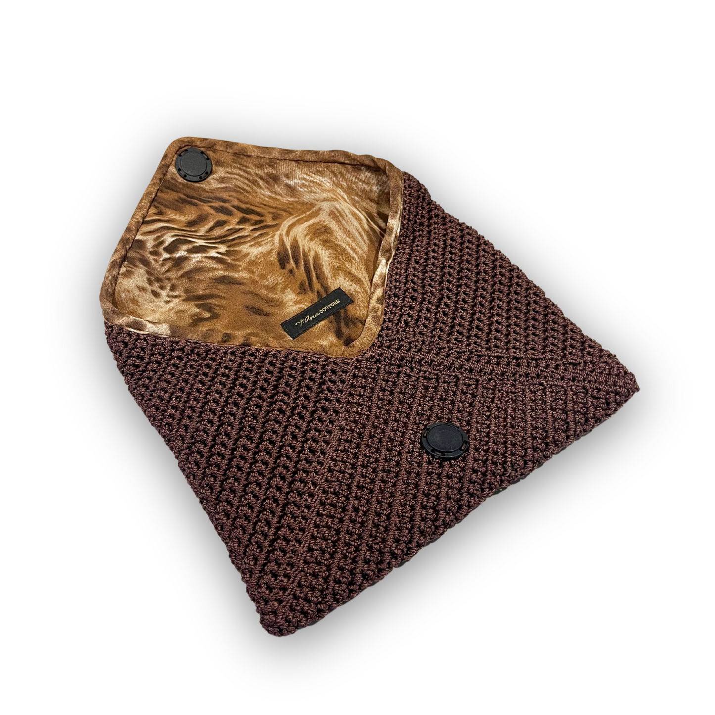 t•Ana Couture Terra Litha Knit Clutch Handbag in rich earthy brown with gold velvet trim and tiger-print interior lining; handmade luxury knit bag styled with brown coat; sustainable, Mediterranean-inspired design. Exceptional luxury design handbag. Elevated luxury brand vibes for high value women.